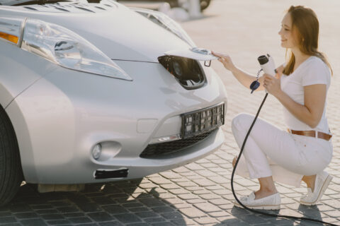 femme qui va recharge sa voiture électrique, elle tient la prise en main