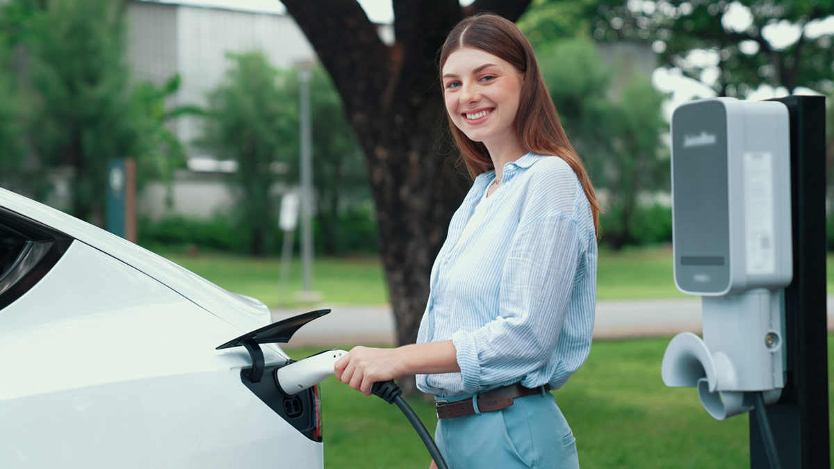 femme souriante recharge sa voiture électrique sur borne de recharge