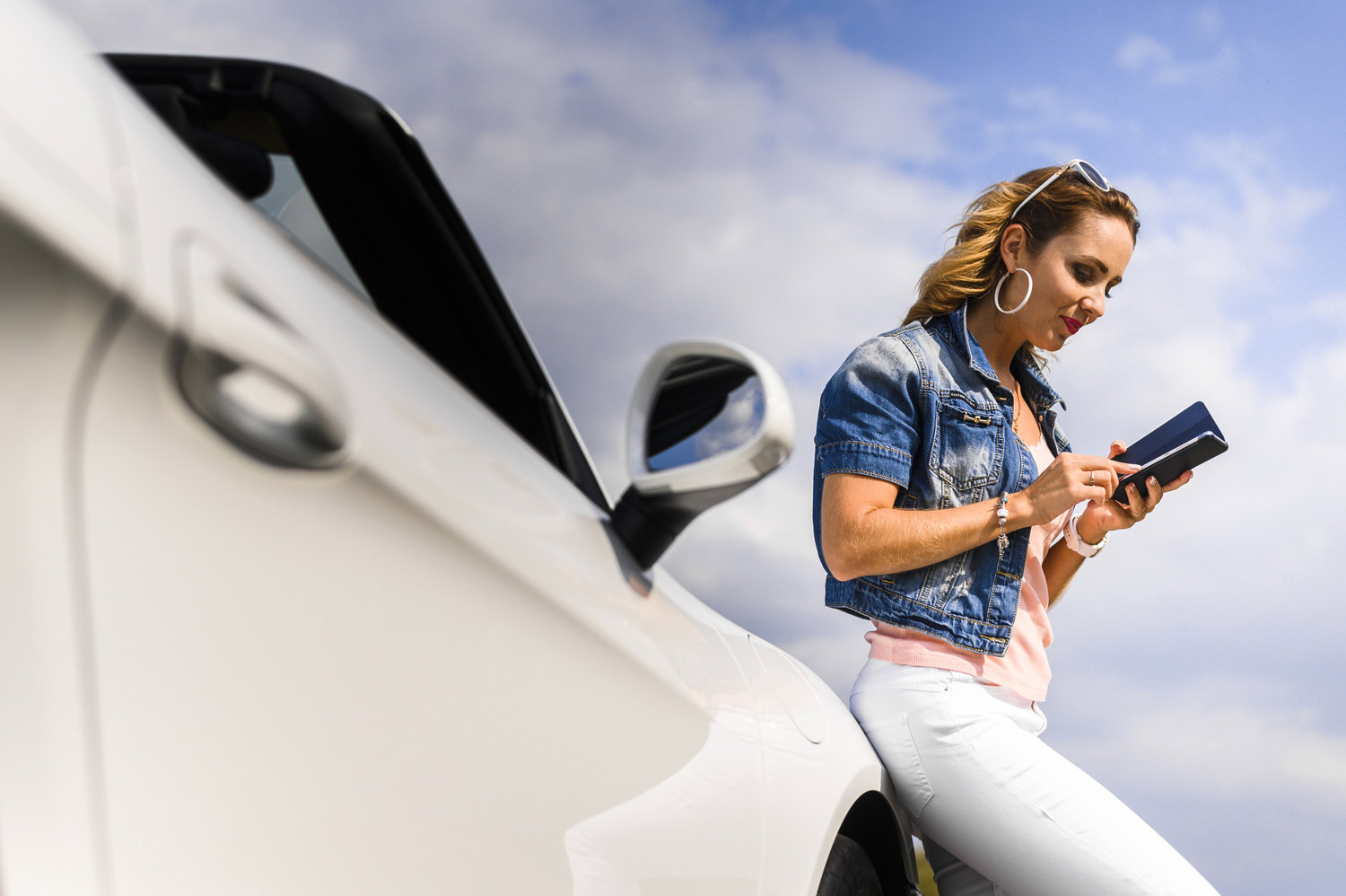 femme qui regarde son téléphone en attendant que sa voiture électrique recharge.