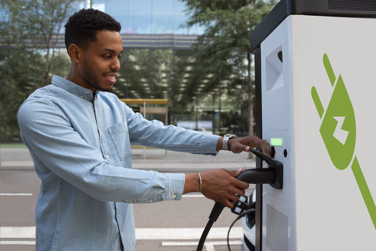 homme à côté d'une borne de recharge pour voiture électrique